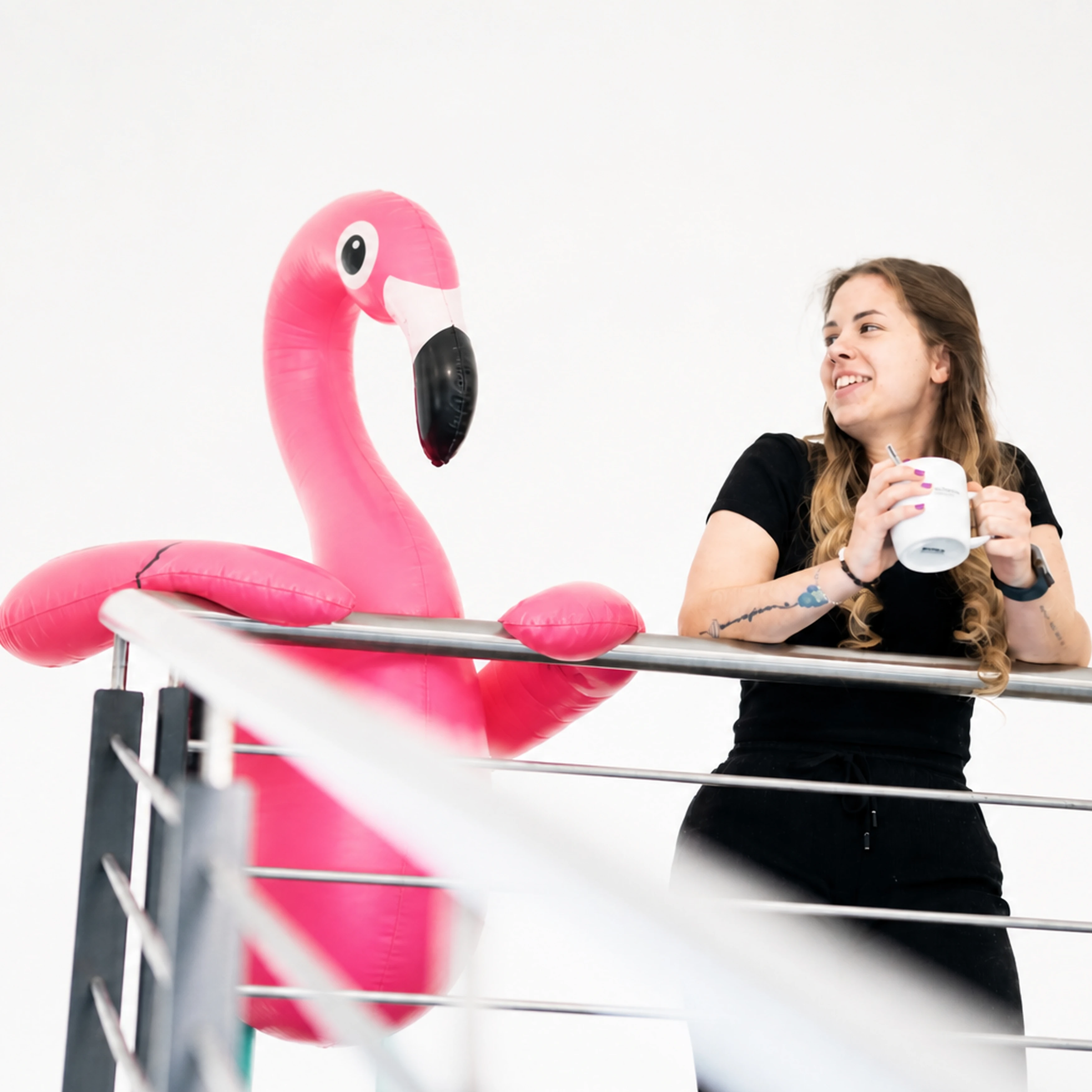 Frau mit Tasse und aufblasbarem Flamingo.