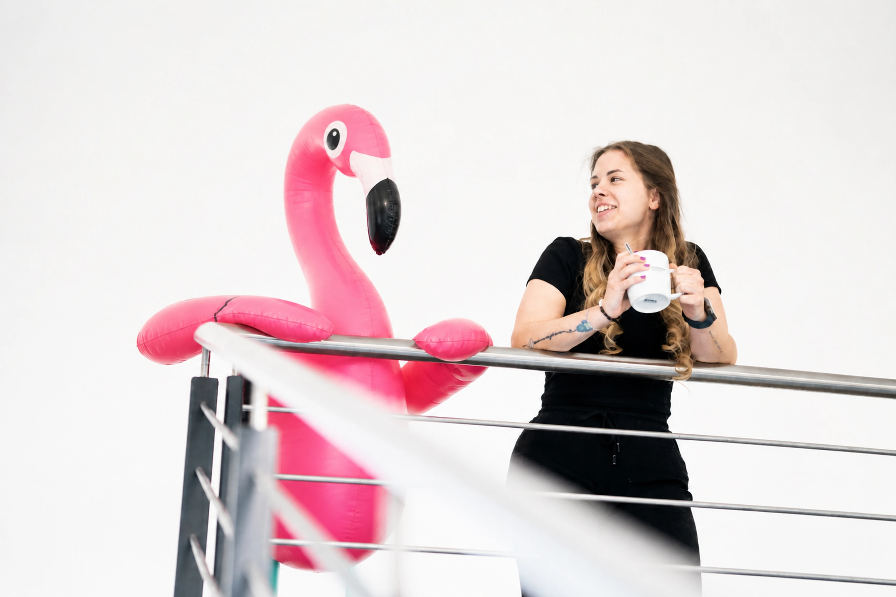 Frau mit Tasse und aufblasbarem Flamingo.