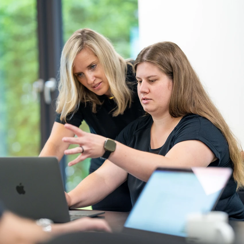 Zwei Frauen diskutieren über Arbeit am Laptop.