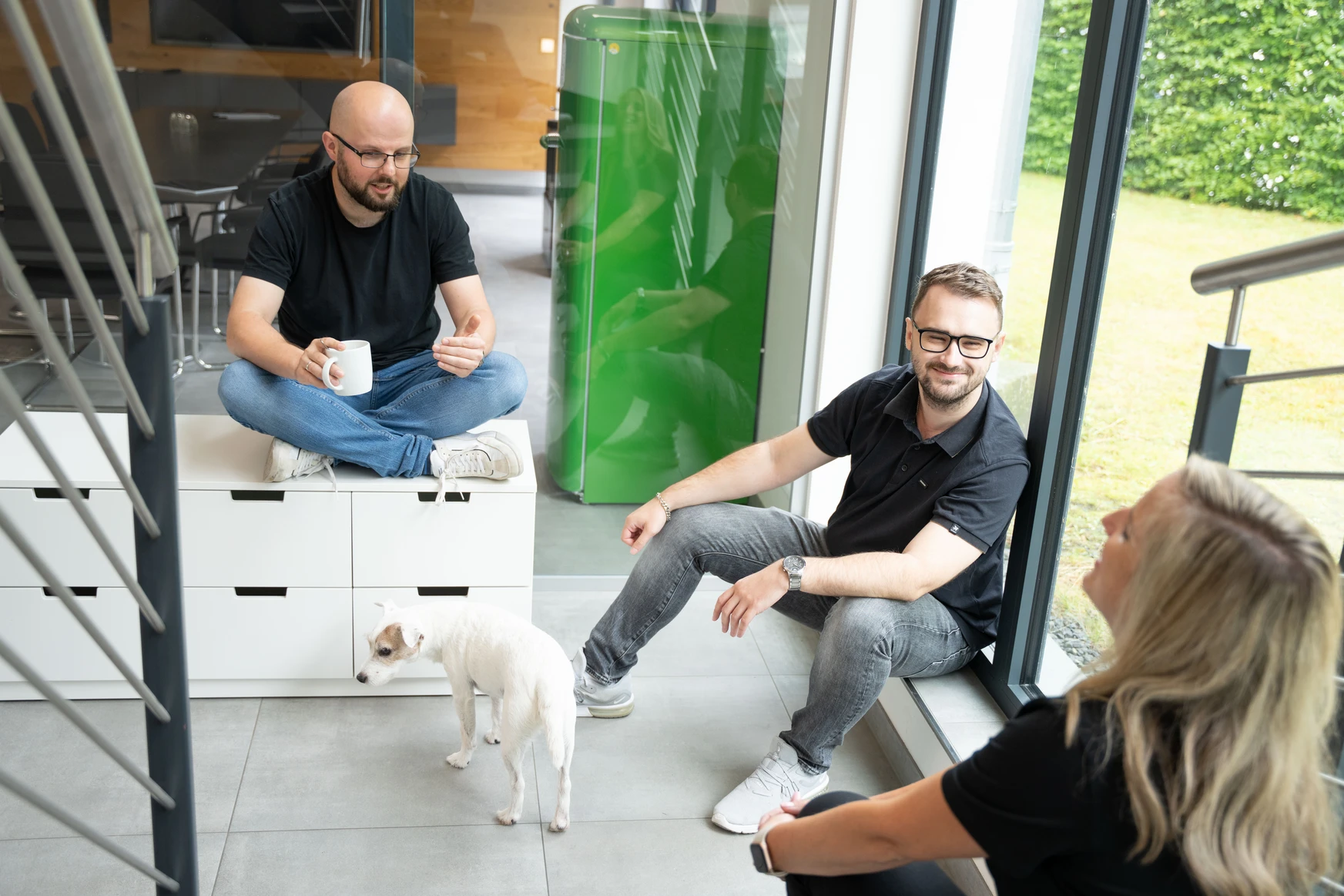 Drei Personen und ein Hund in einem Büro.