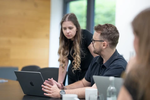 Mann und Frau diskutieren an einem Tisch mit Laptops.
