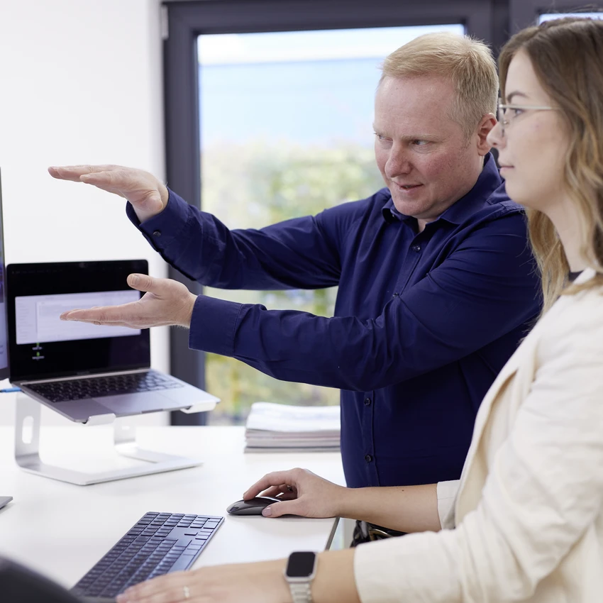 Zwei Personen arbeiten an einem Computer im Büro.