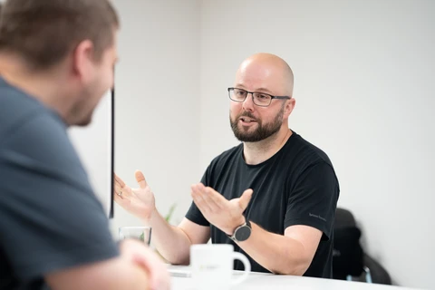 Zwei Männer sprechen am Schreibtisch.