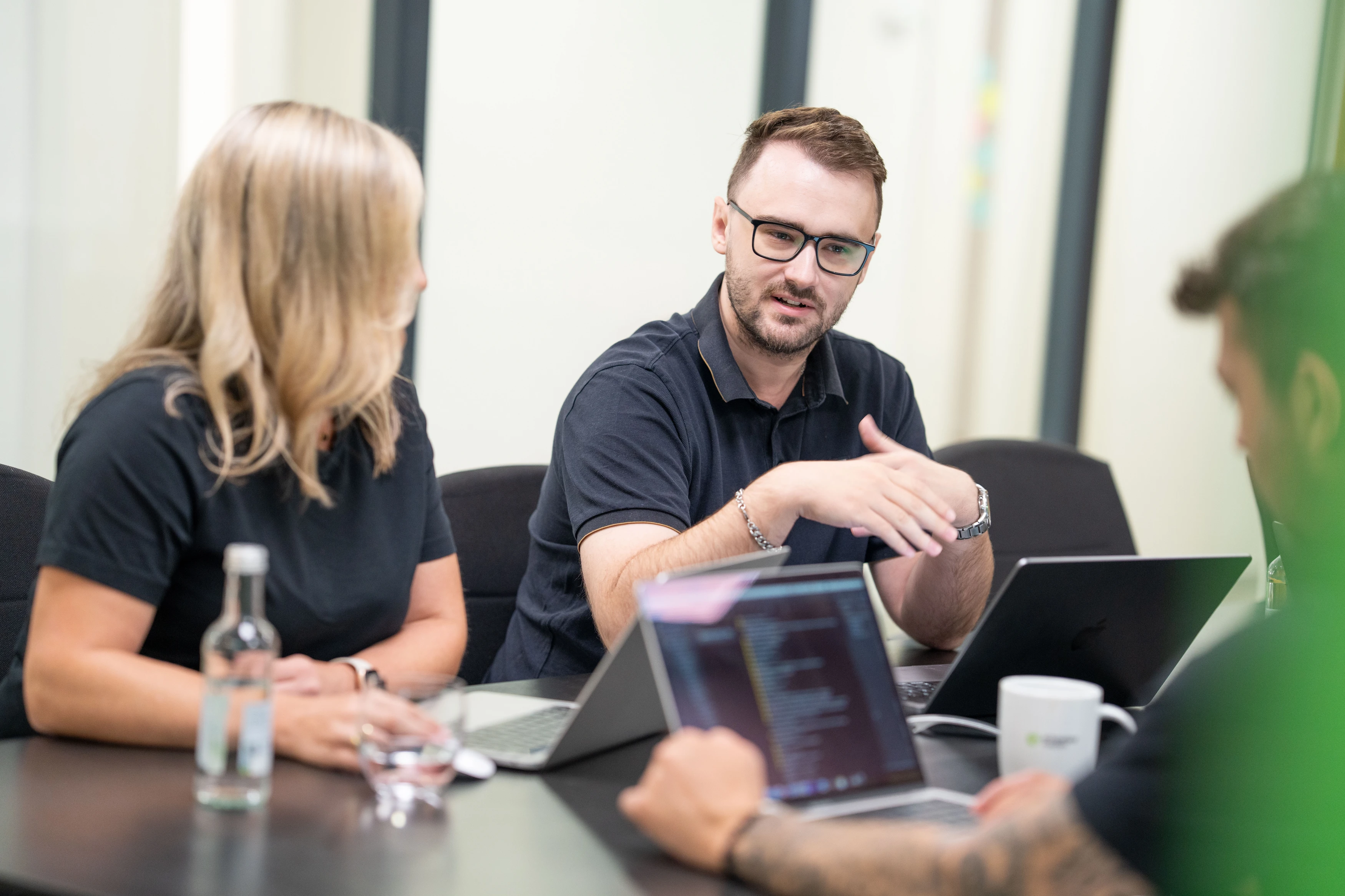 Kollegen diskutieren an einem Tisch mit Laptops.