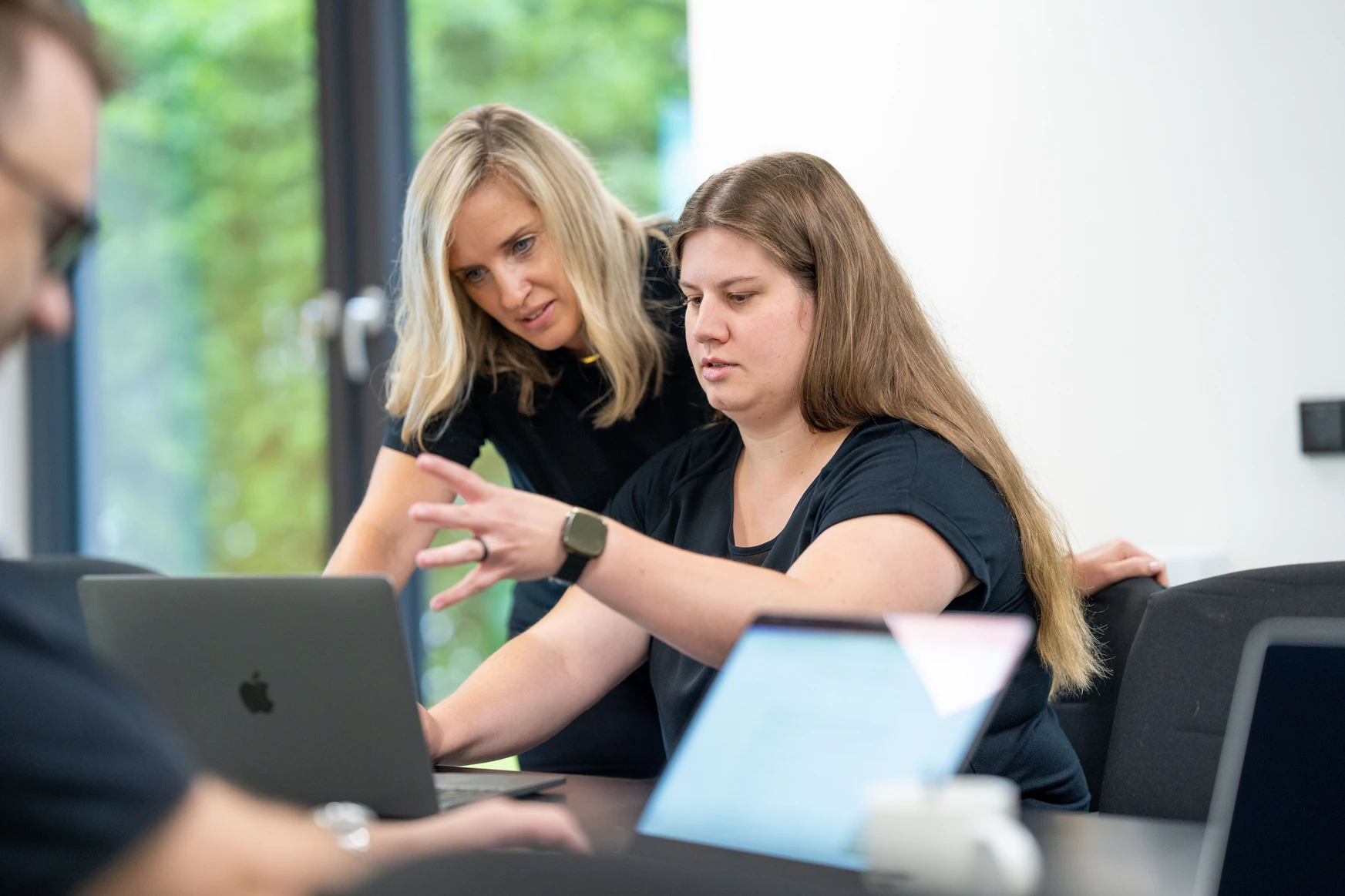 Zwei Frauen arbeiten gemeinsam an einem Laptop.